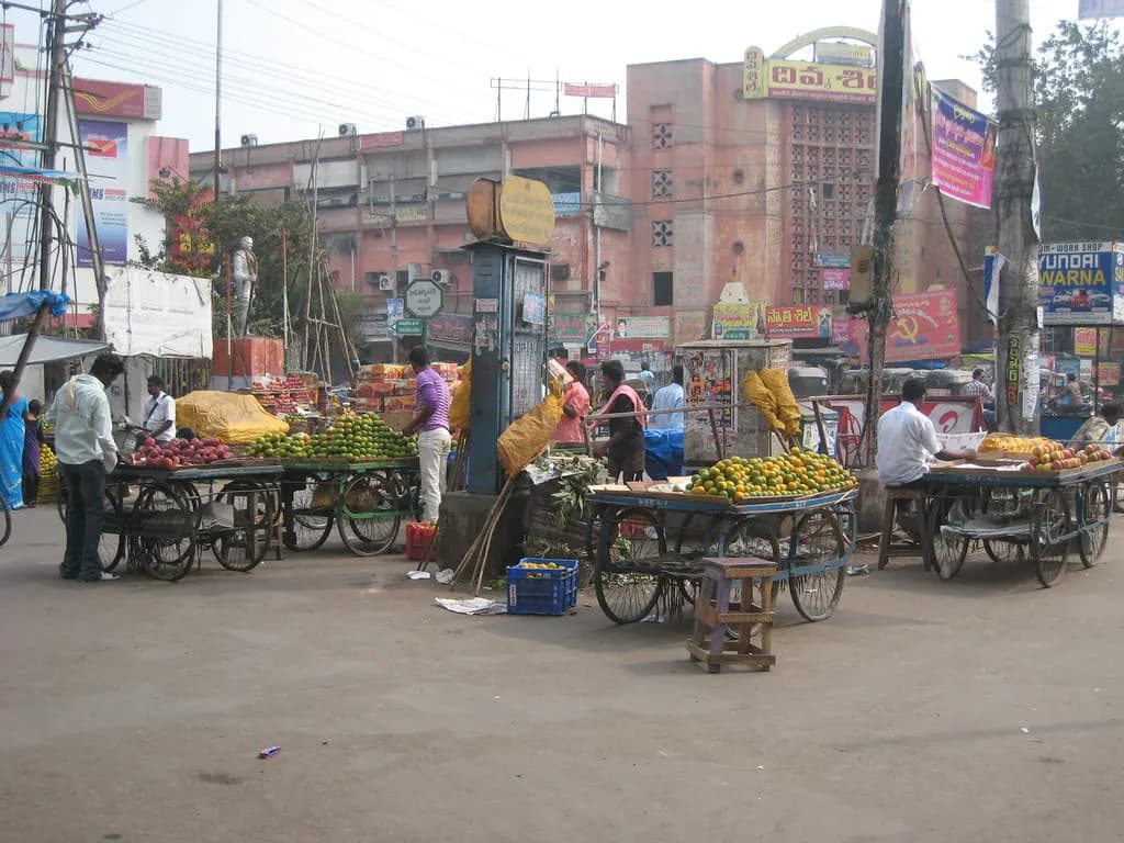 Fruit and vegetable carts in front of shops and commercial buildings on a Vijayawada street