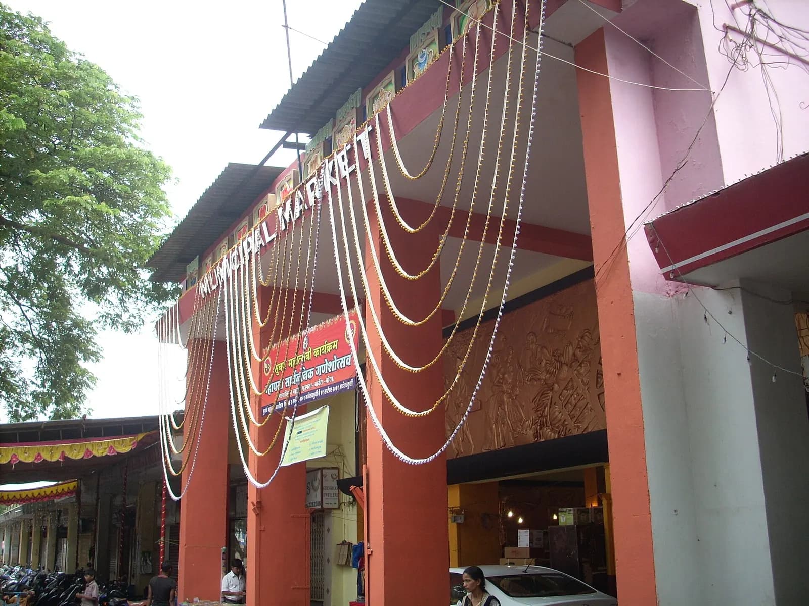 The entrance to Mapusa's municipal market, an orange-and-white arched gateway decorated with strings of flowers