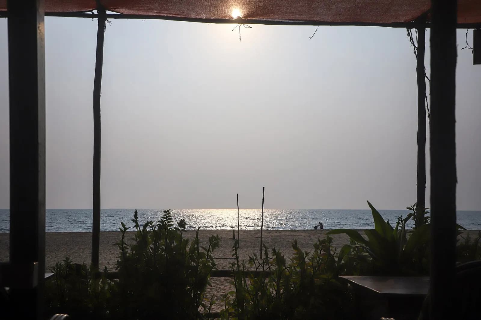 View from inside a beach shack at Palolem, Goa, looking out over the sand and sea at sunset