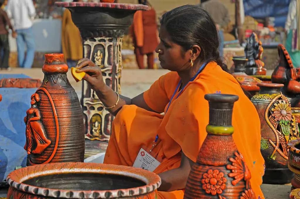 An artisan arranging decorated terracotta pots at her stall at the Surajkund crafts fair in Faridabad