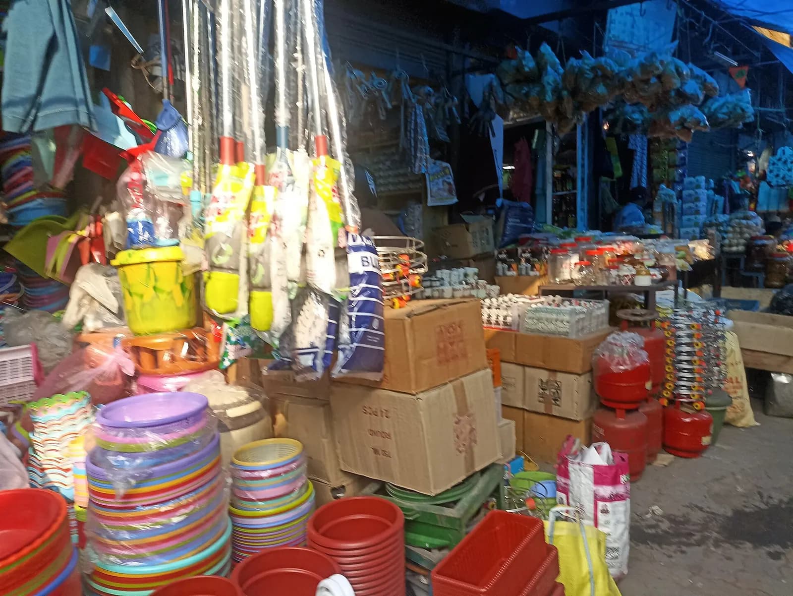 Shopfronts in Sakchi main market, Jamshedpur, stacked with plastic buckets, tubs, mops and cartons of household goods