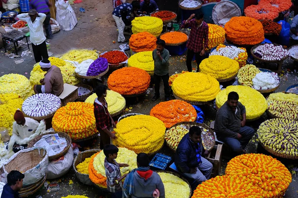 Traders selling heaps of marigold and chrysanthemum flowers at a crowded wholesale flower market in Chickpet, Bengaluru
