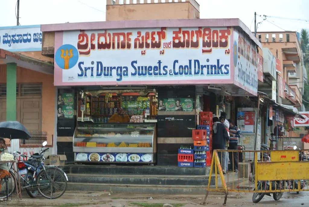 A small sweets and cool drinks shop in Karnataka with its name painted in large Kannada script above English