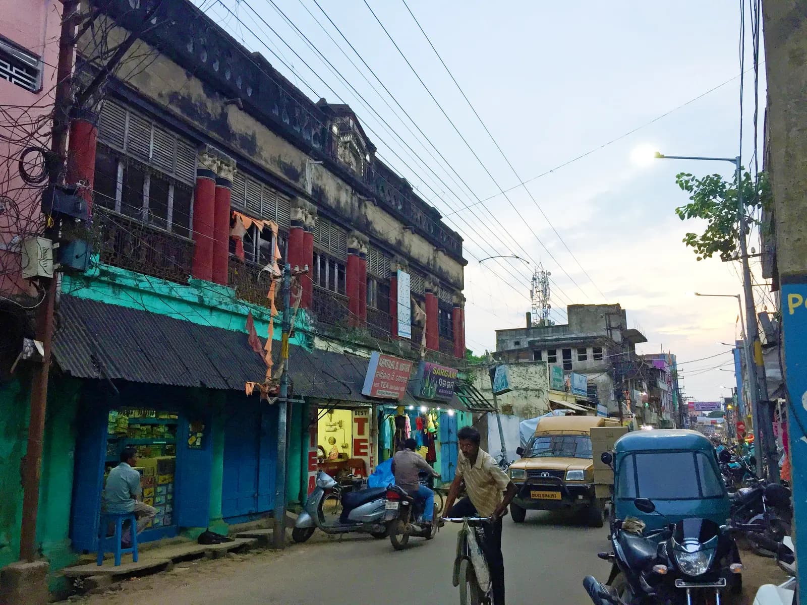 An old two-storey building with ground-floor shops on a busy street in Motiganj bazar, Balasore, Odisha