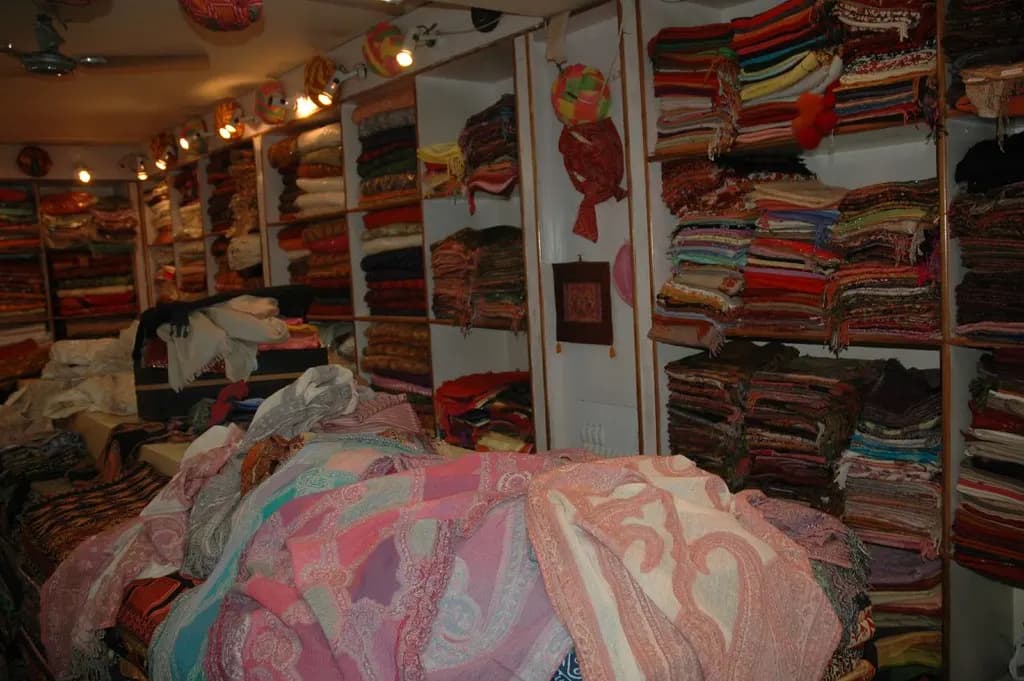 Shelves stacked with folded shawls and textiles inside a shop in Jaipur