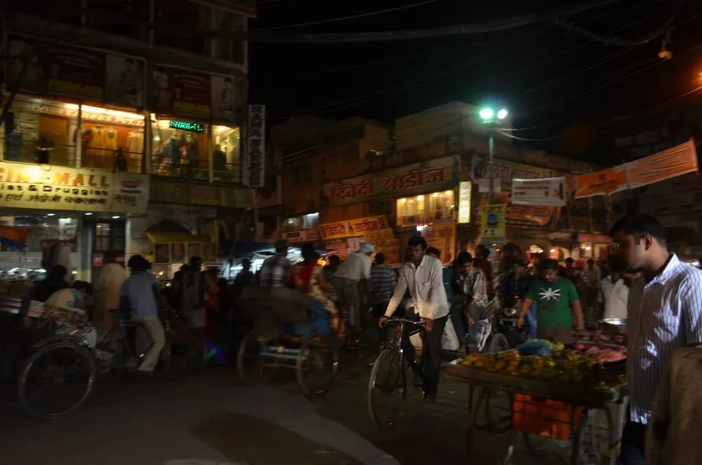 Shops, fruit carts and cycle-rickshaws on a busy street in the Hazratganj market area of Lucknow at night