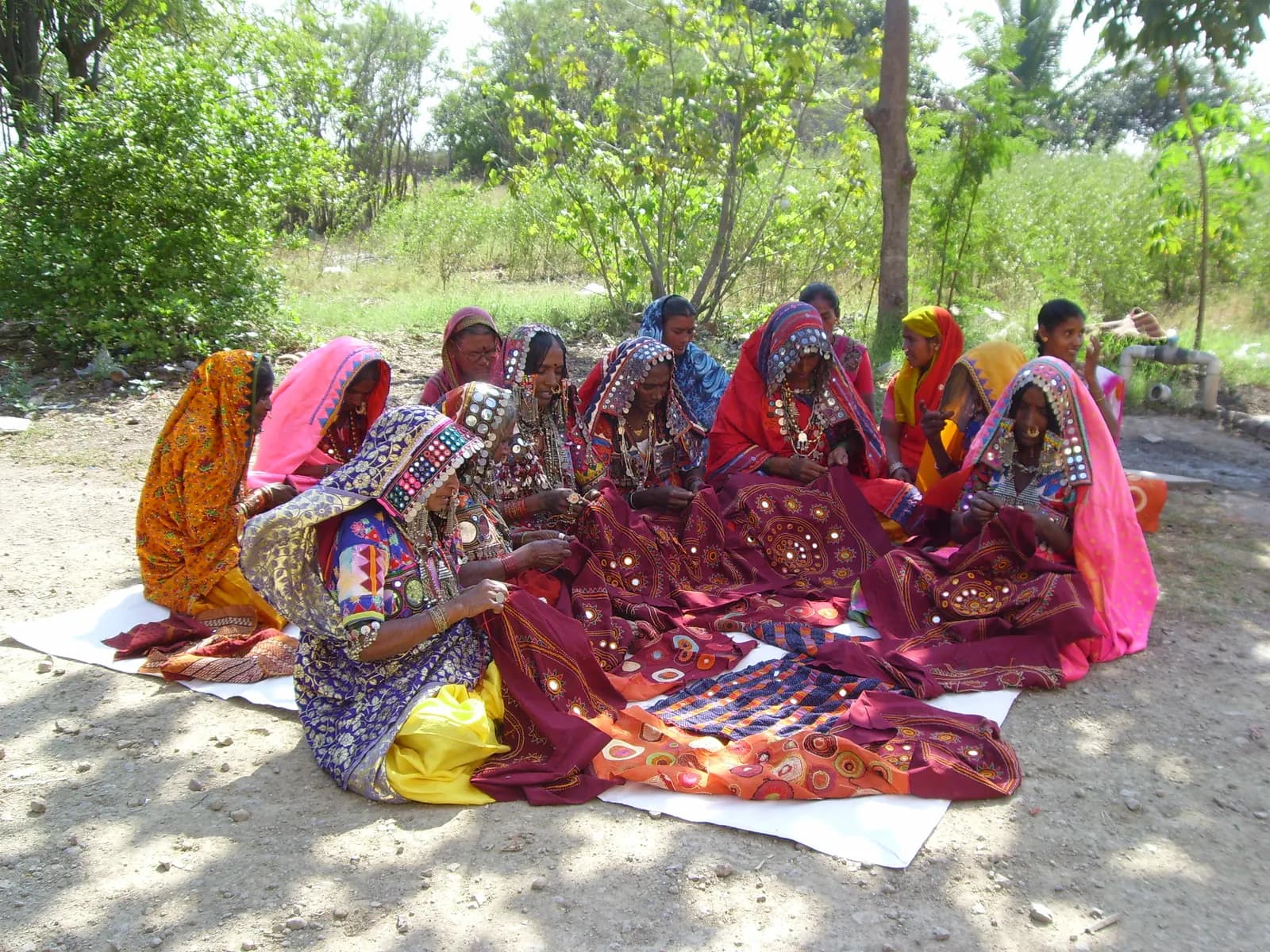 A group of Lambani women doing traditional mirror embroidery together outdoors