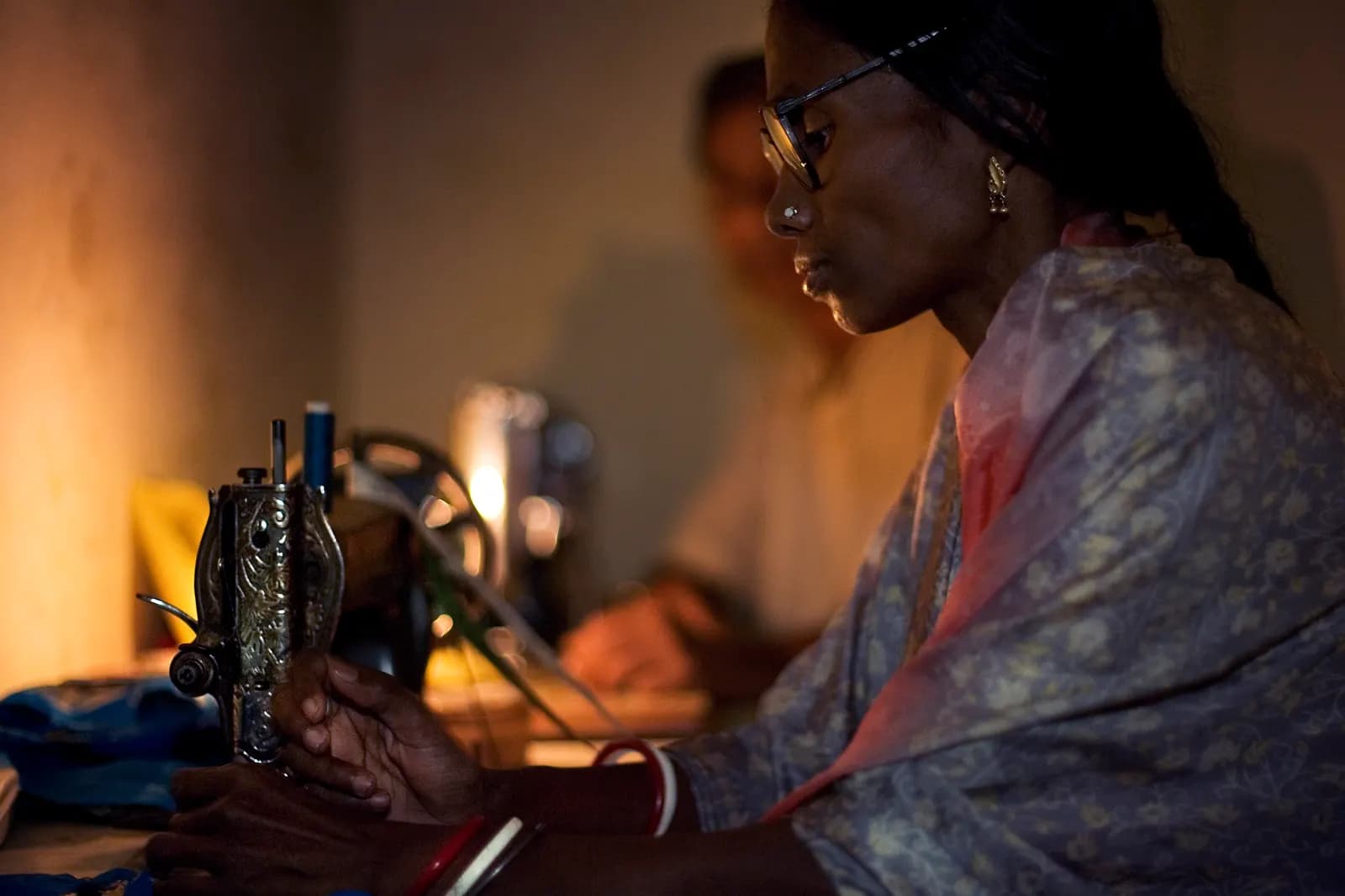 A woman tailor working at a sewing machine in a small workshop