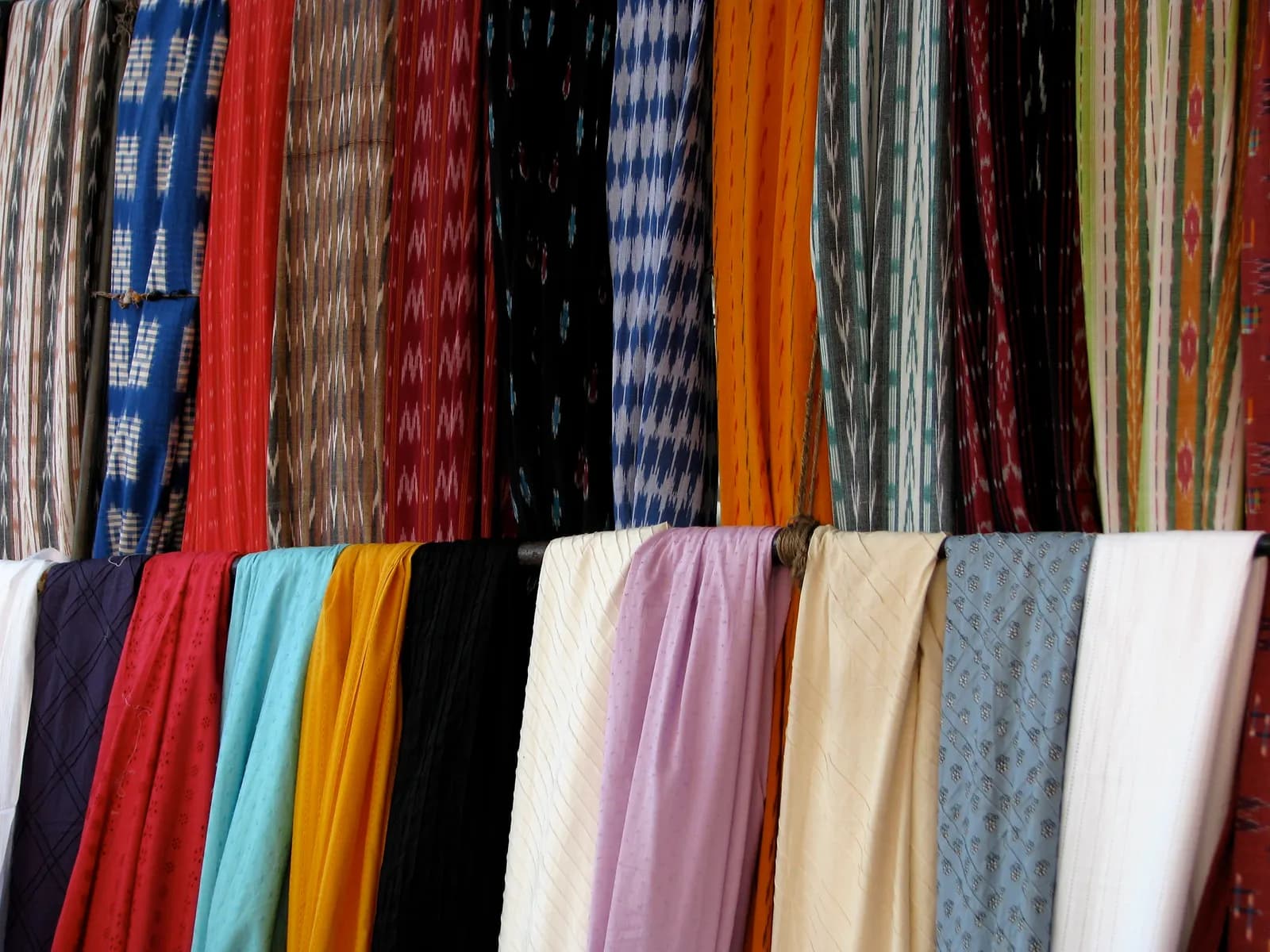 Bolts of brightly coloured fabric stacked for sale at a shop in Chennai