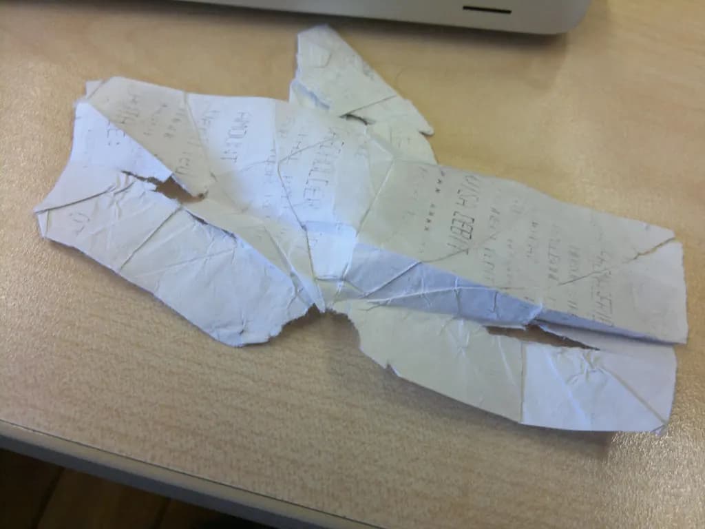 A crumpled, faded paper receipt lying on a desk next to a laptop
