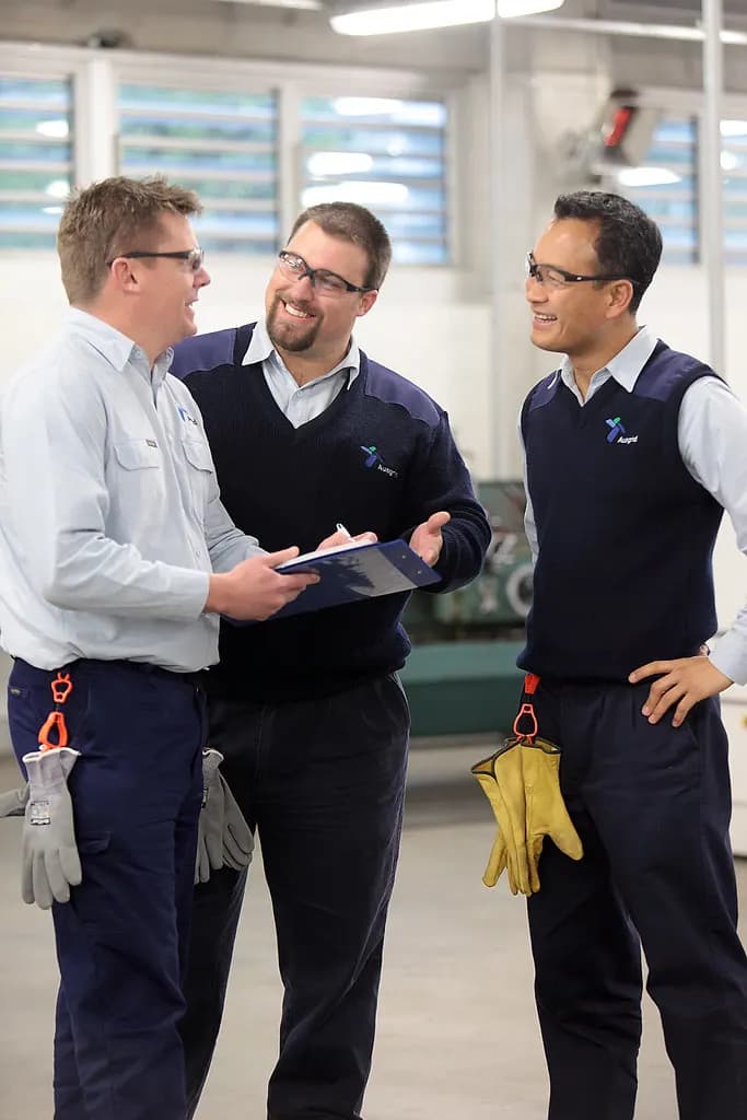 Apprentices in work uniforms talking with a trainer in a training workshop
