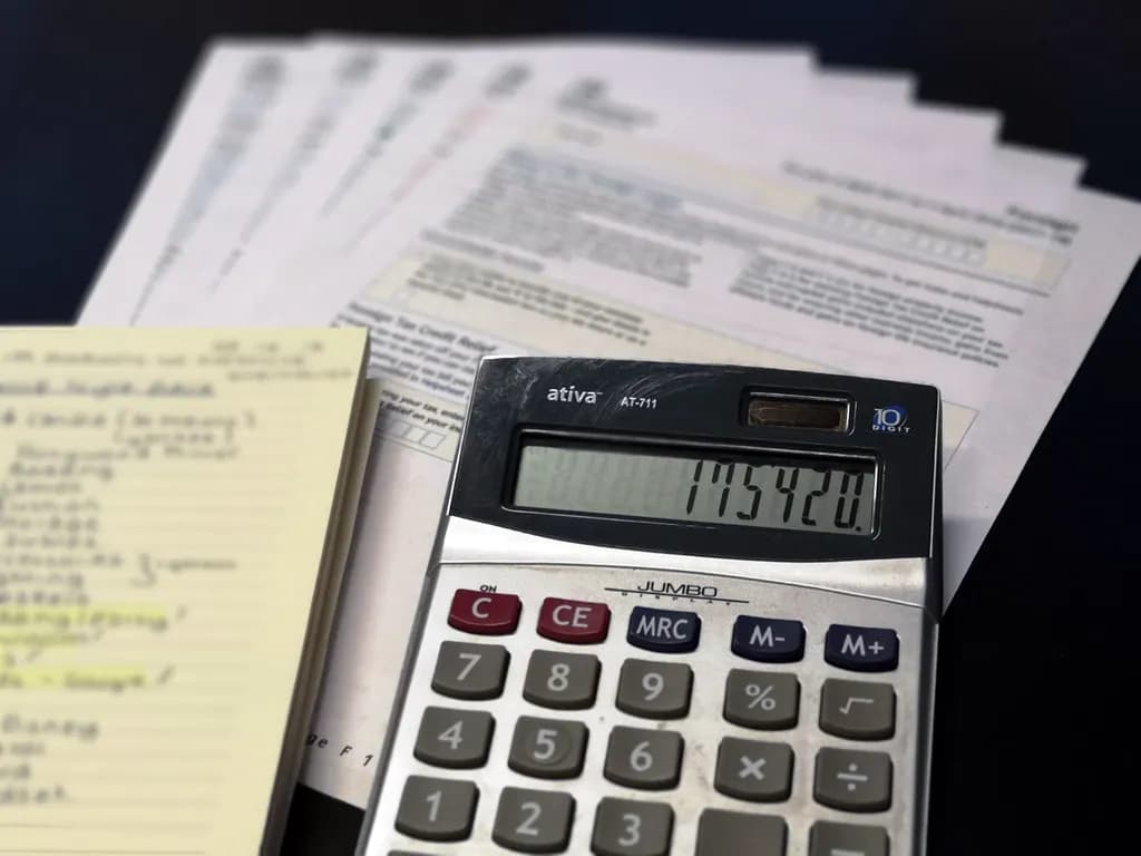 A calculator beside tax forms and paperwork on a desk
