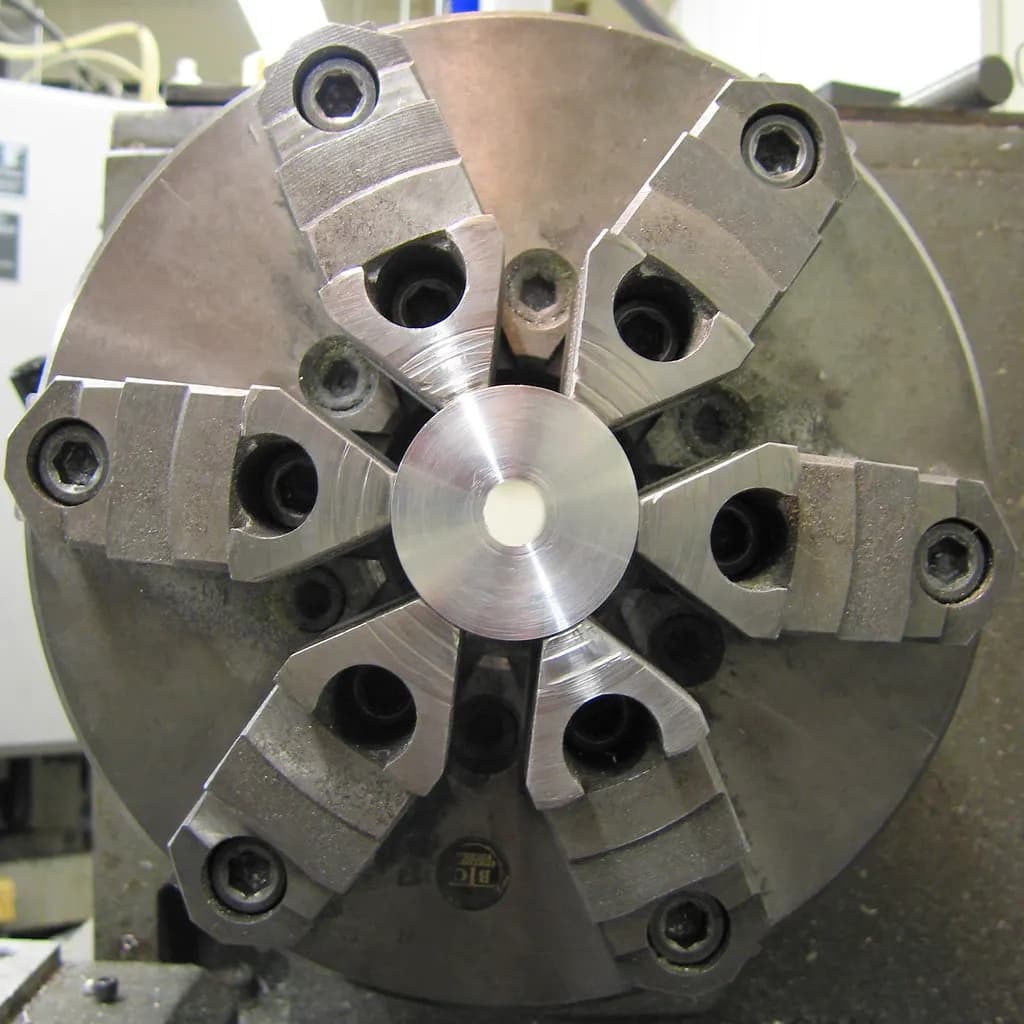 Close-up of a six-jaw chuck holding a machined part on a metalworking lathe