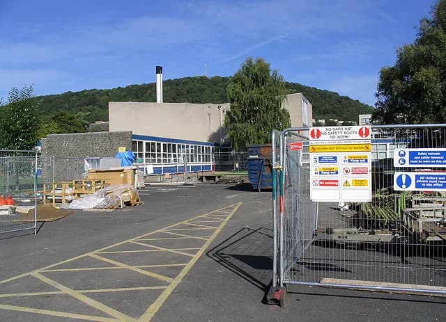 Fenced building site with safety signs requiring hard hats and safety boots, Scottish Borders