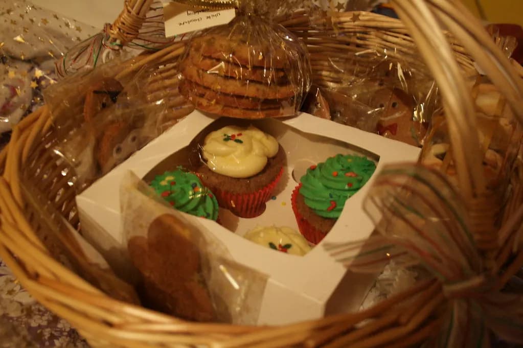 A wicker basket of homemade Christmas cupcakes and biscuits wrapped in cellophane