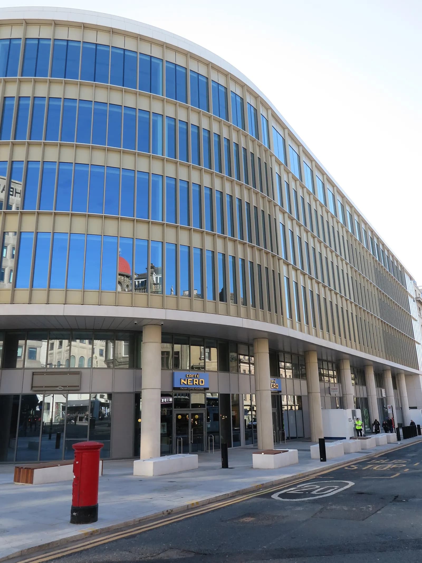 Curved glass-fronted HMRC office building at Pilgrim's Quarter on Pilgrim Street, Newcastle upon Tyne, with a red postbox in front