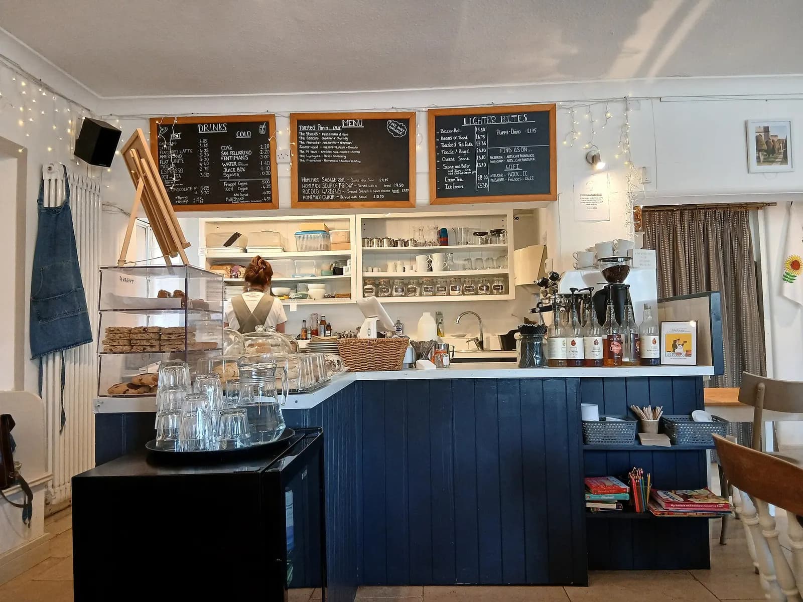 The serving counter, cake display and chalkboard menus of a small village café in Painswick, Gloucestershire