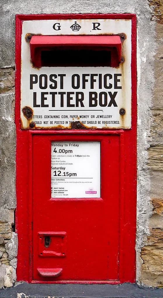 A red Royal Mail post box set into a brick wall