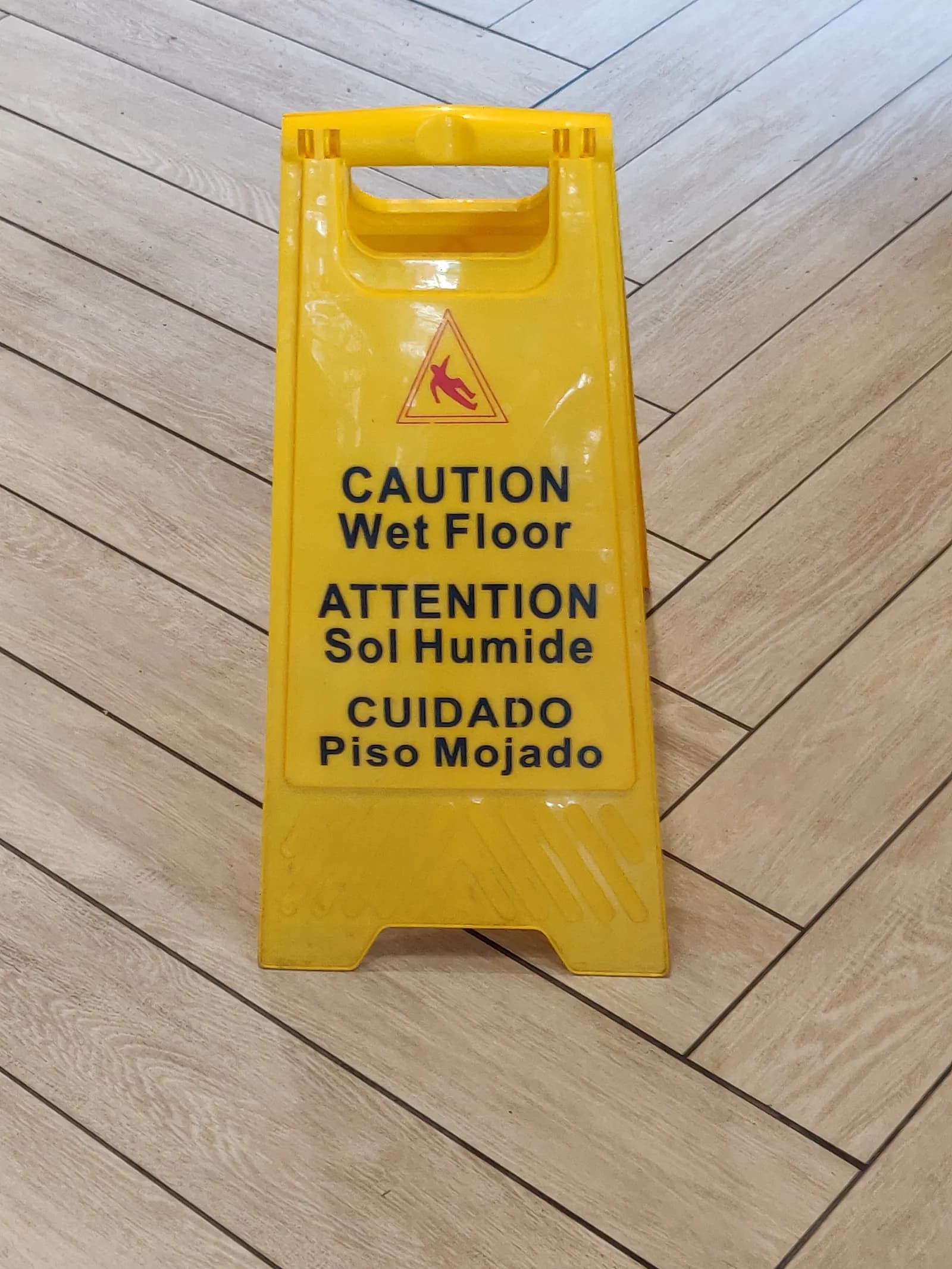 A yellow 'Caution wet floor' sign standing on a wooden floor