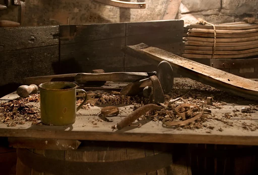 Inside a carpenter's workshop with hand tools hanging above a wooden workbench