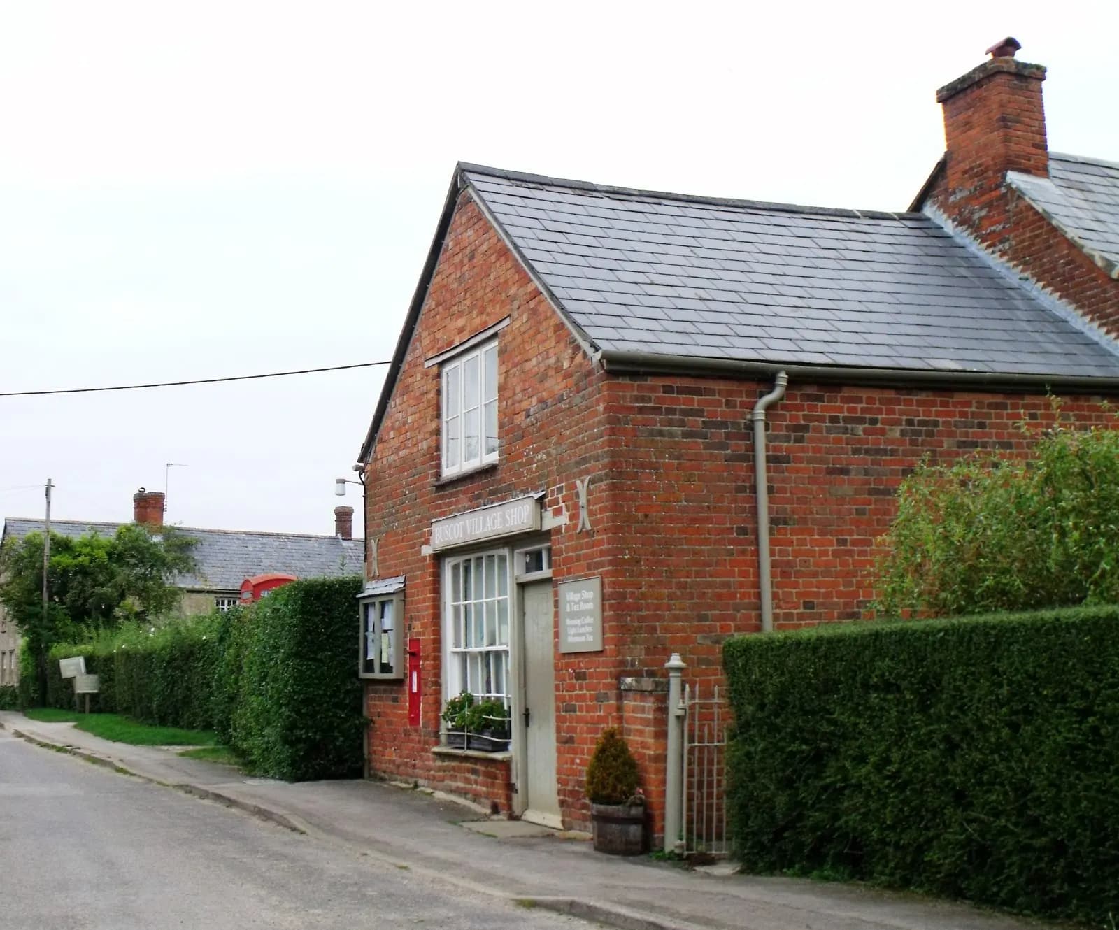 A small brick-built village shop with a post box in Buscot, Oxfordshire