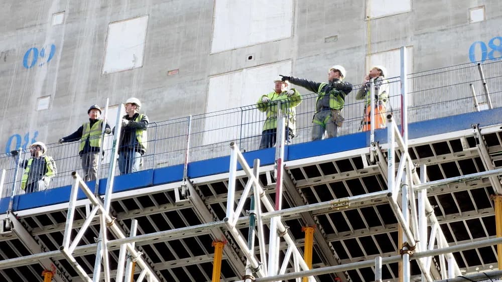Construction workers in hard hats and hi-vis jackets on a building deck at One St Peter's Square, Manchester