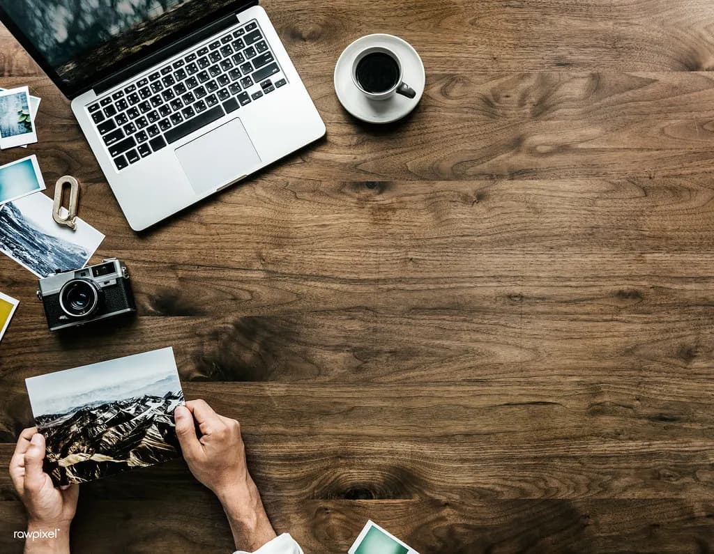Laptop, notebook and coffee on a wooden desk seen from above