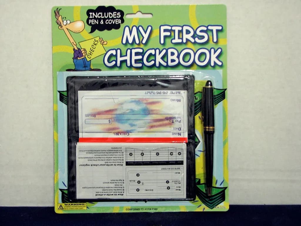 Paper checkbook with blank checks and a pen in retail packaging