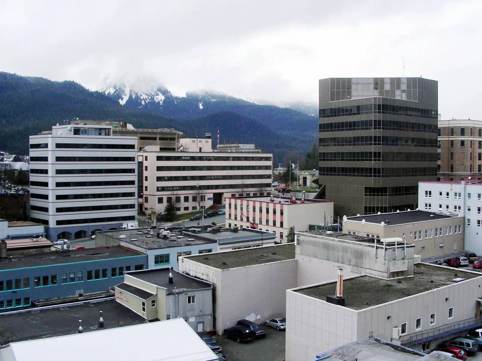 Shops and buildings in downtown Juneau, Alaska, beneath forested mountains