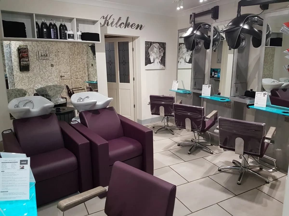 A hair salon interior with two backwash basins, styling chairs and mirrored stations
