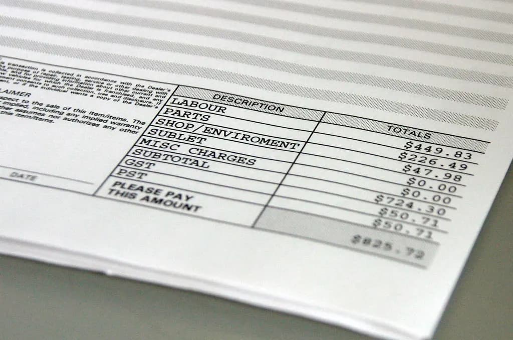 Close-up of a printed invoice showing labour, parts and a total under 'please pay this amount'