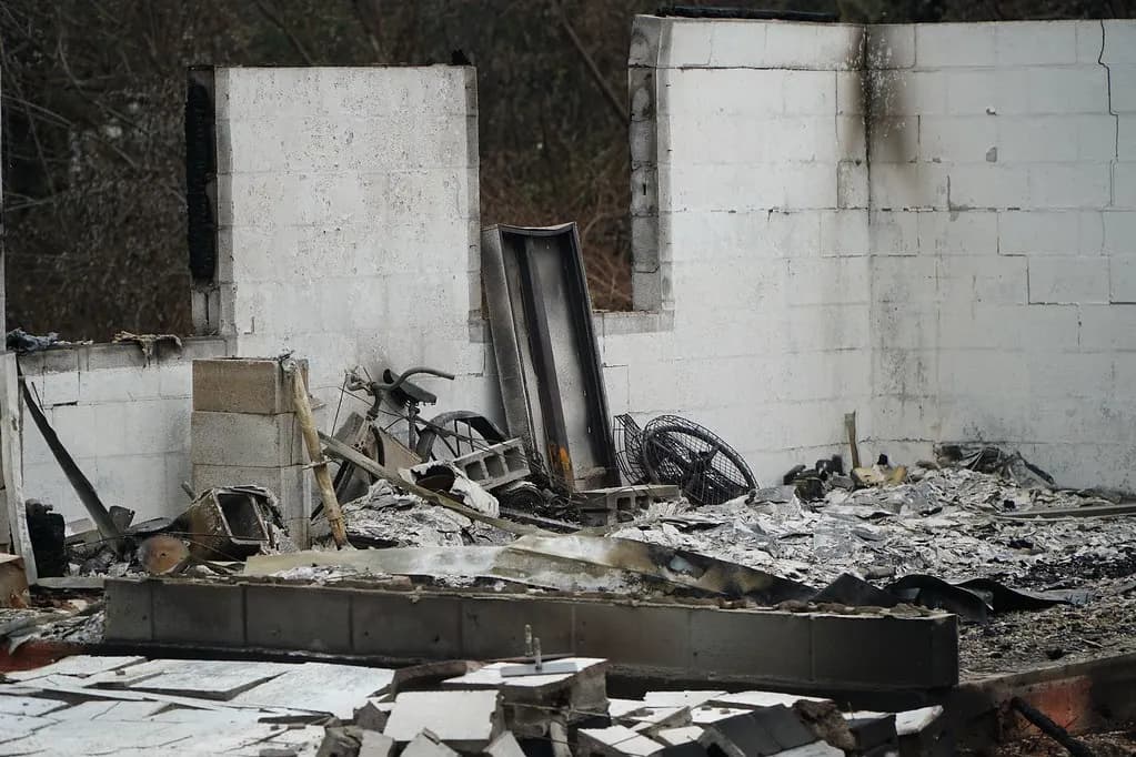 Burned-out shell of a concrete-block building with charred debris and twisted metal inside