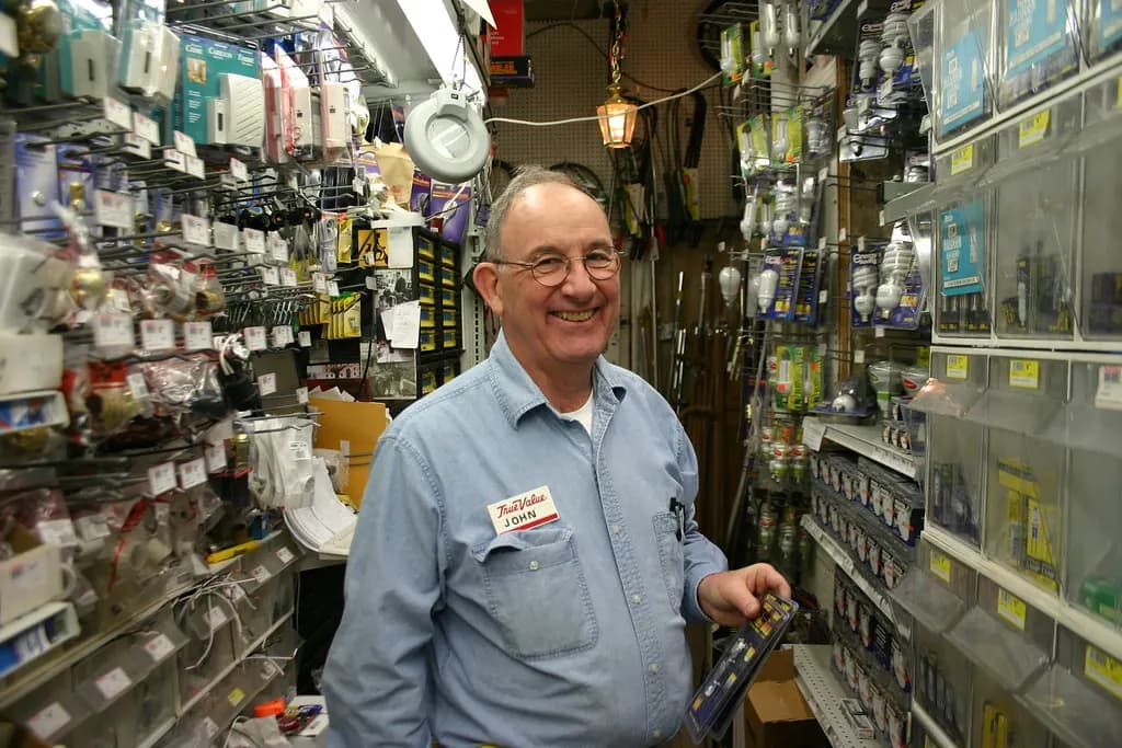A smiling employee standing in a packed aisle of Frager's Hardware, a neighborhood hardware store in Washington, D.C.