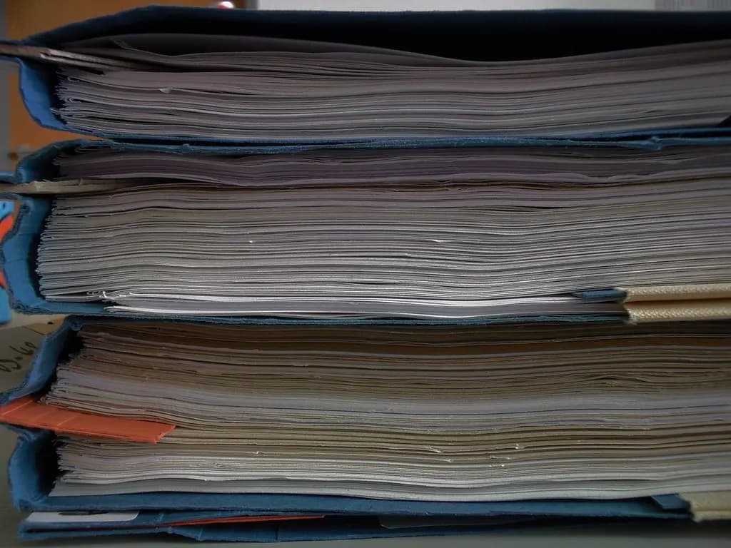 Stack of thick blue ring binders filled with paper records