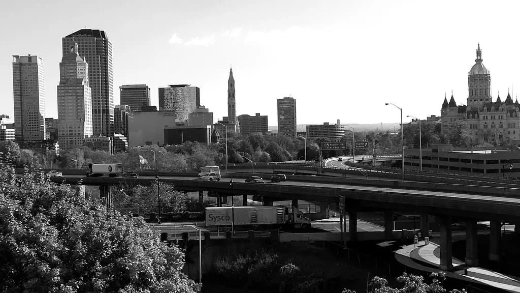 Black-and-white view of downtown Hartford's office towers and the State Capitol beyond a highway