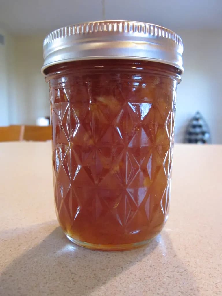 A sealed glass jar of homemade apple jam on a kitchen counter