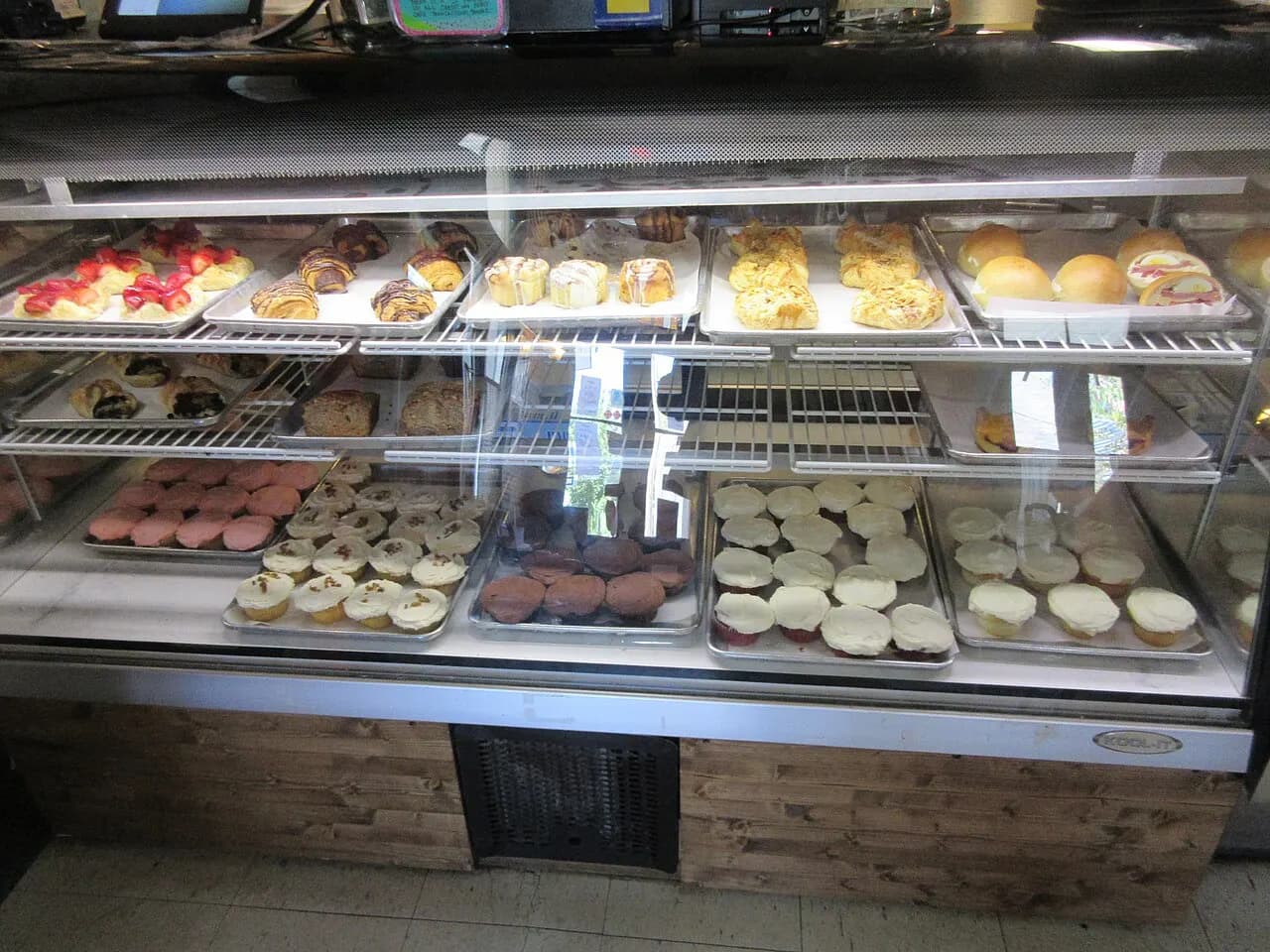 A bakery display case of pastries, cupcakes and muffins inside a small New Orleans cafe