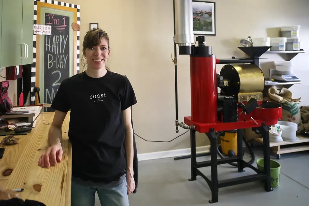 Woman owner of a coffee roastery standing beside her roasting machine in Plymouth, Michigan