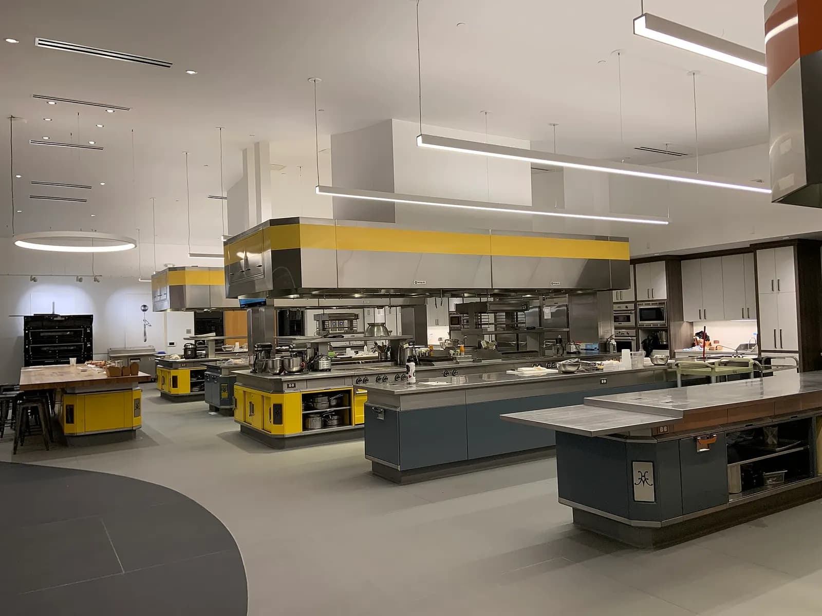 Large commercial kitchen with stainless steel cooking islands, range hoods and prep stations