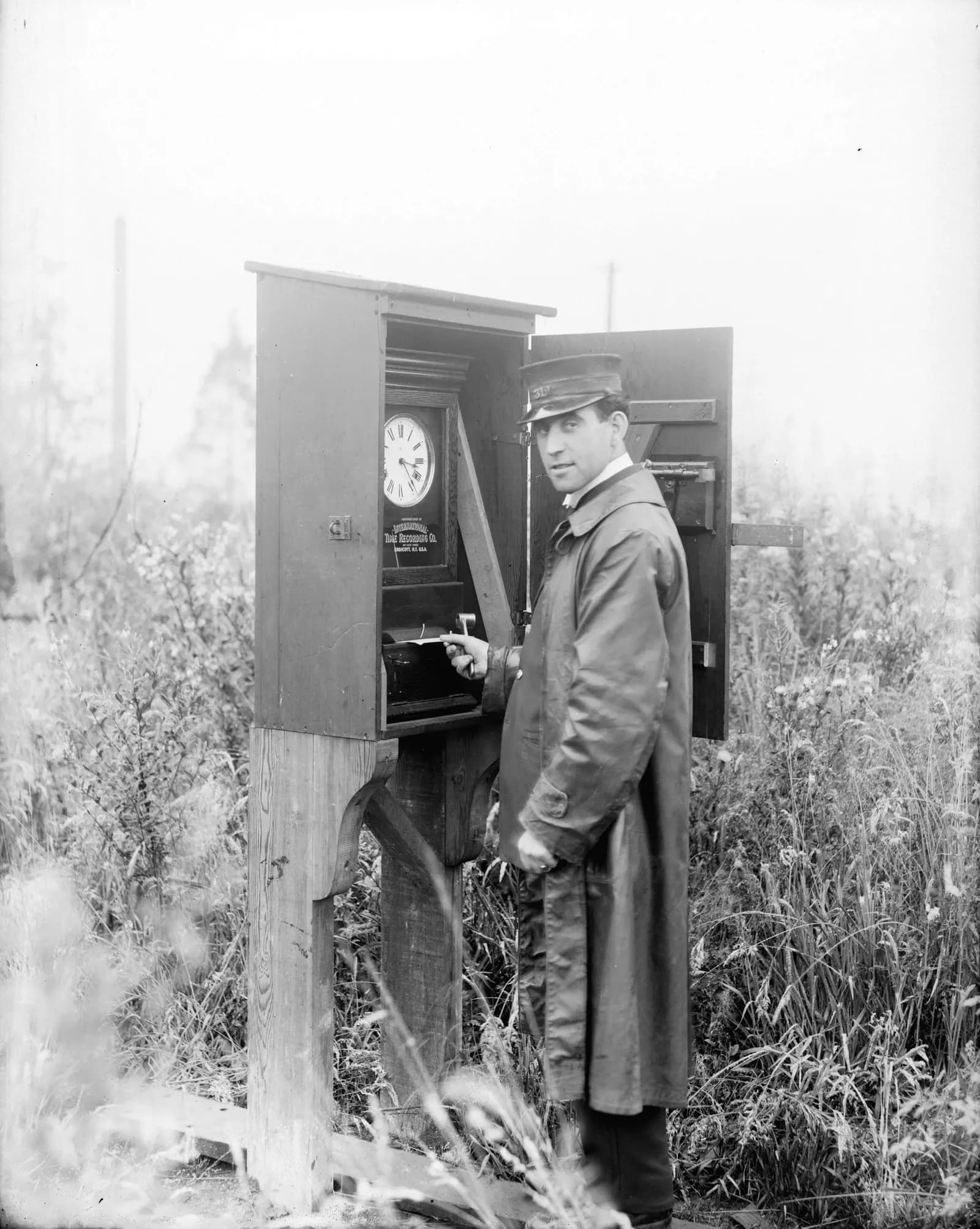 Historic photo of a streetcar motorman recording his time at a wooden time-clock box at the end of a line