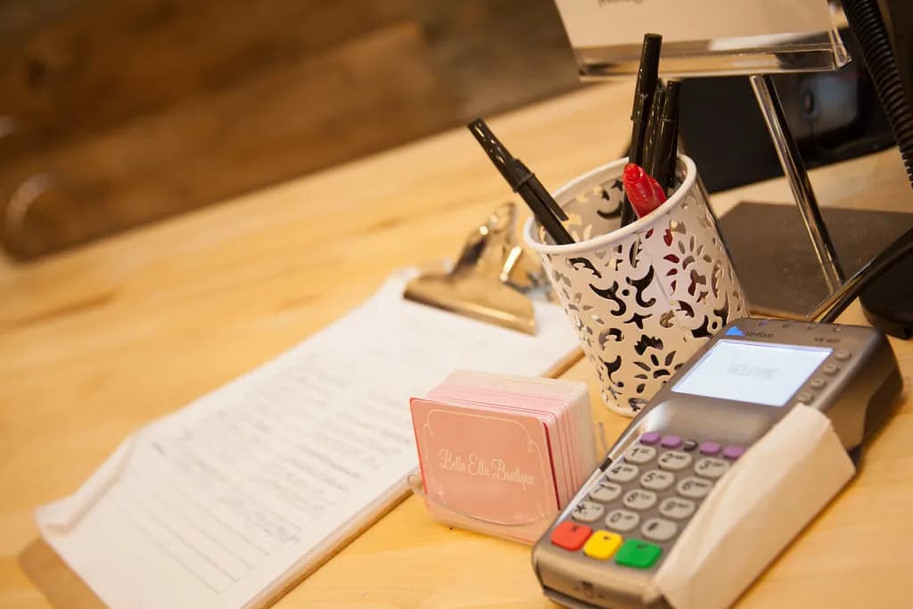 Card payment terminal, order clipboard and pens on a boutique checkout counter
