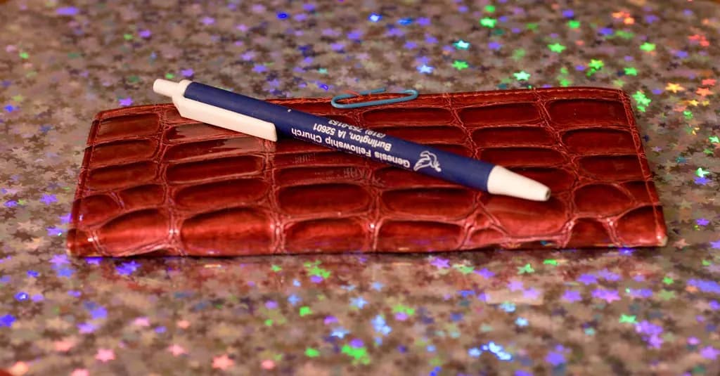 A checkbook register and pen used to balance a bank account