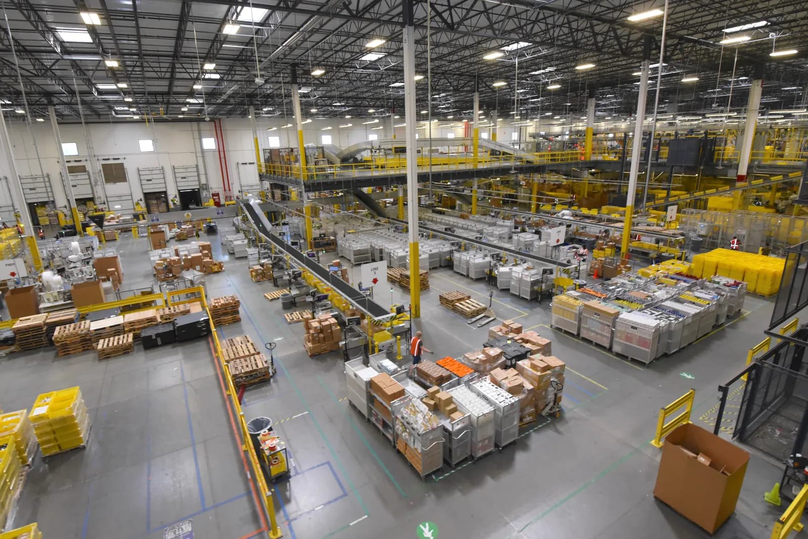 Inside a large e-commerce fulfillment center with conveyor belts, pallets of boxes and carts of sorted parcels
