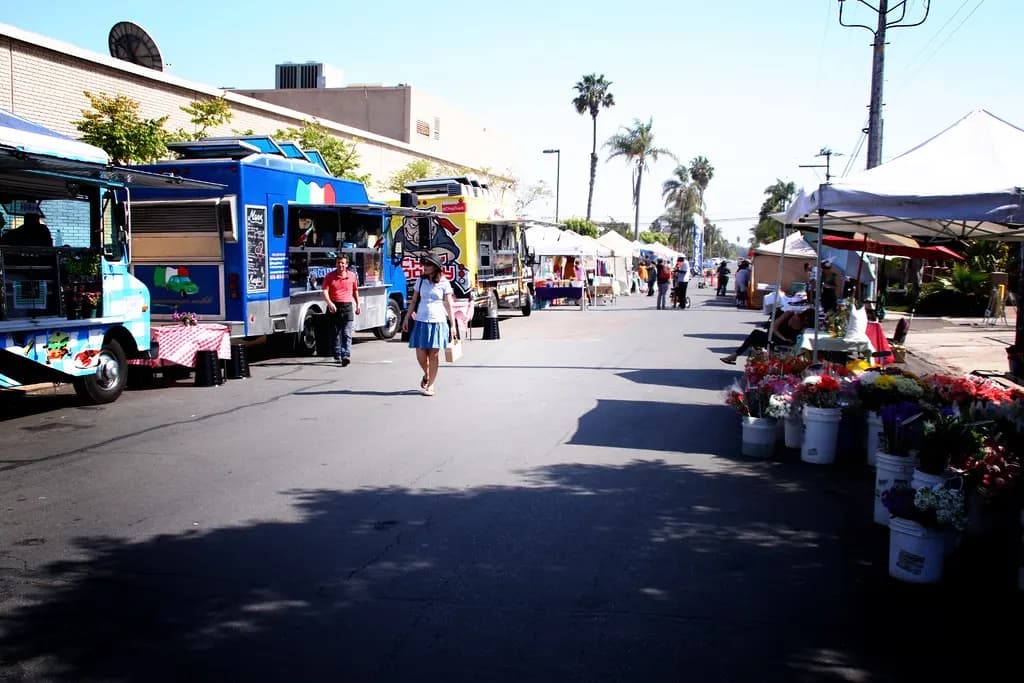 Food trucks and flower stalls lining a street at the North Park farmers market in San Diego