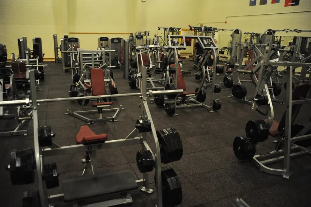 A strength training floor filled with plate-loaded machines, benches and weight plates on rubber flooring