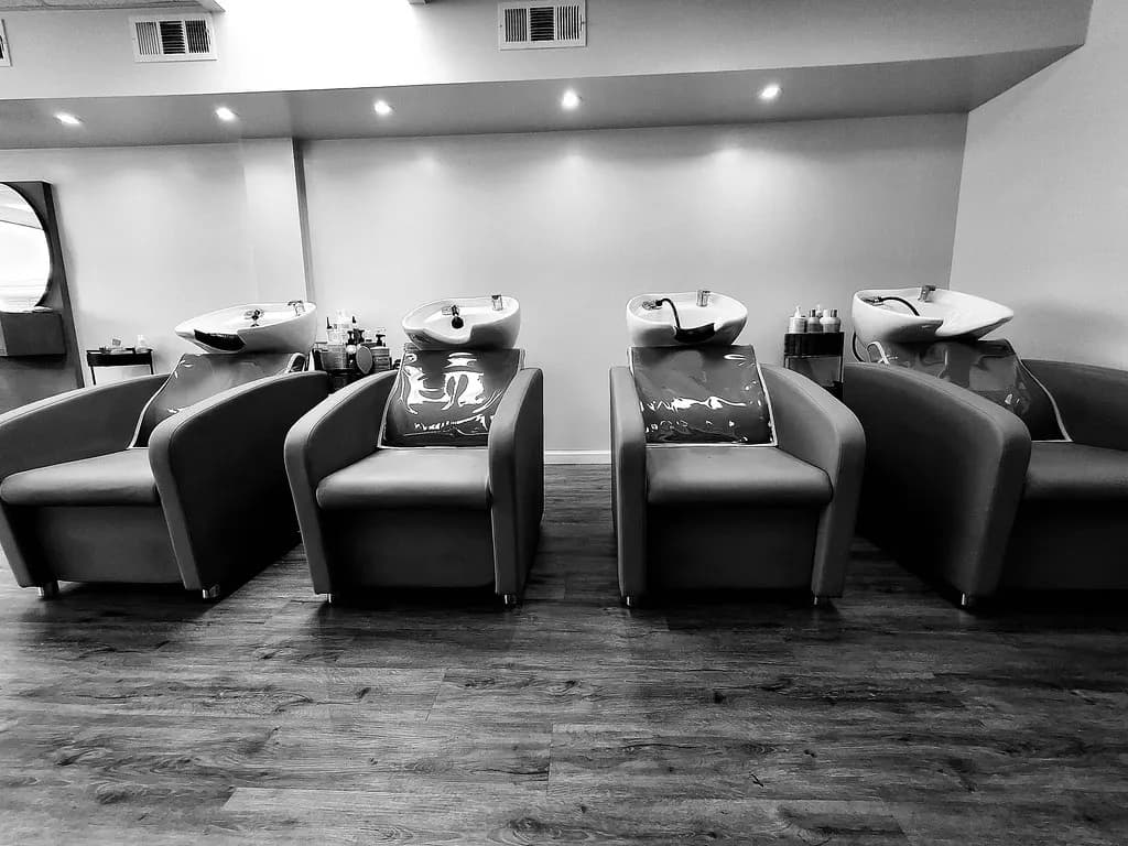 A row of four backwash shampoo units with reclining chairs in a hair salon