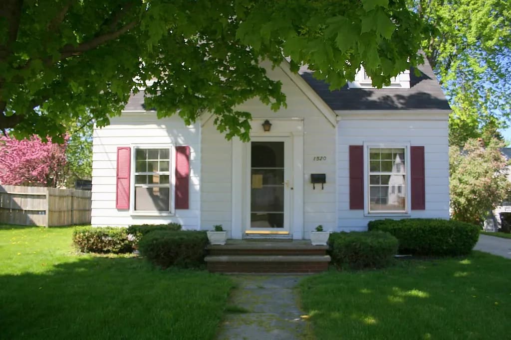 Freshly trimmed shrubs and a mowed lawn in front of a small white house
