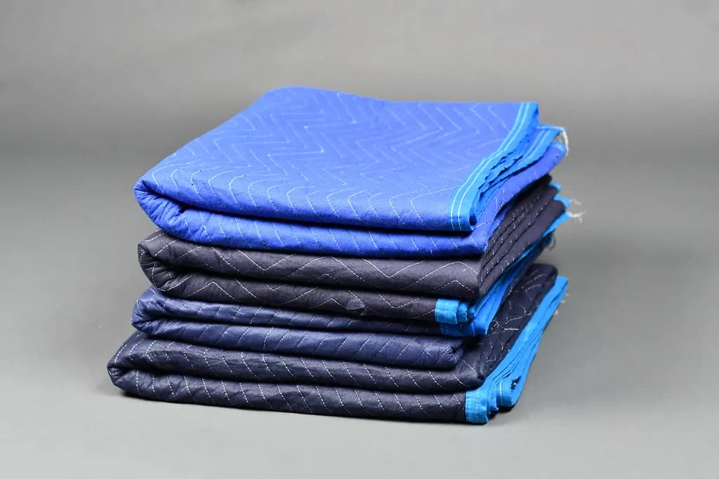 A stack of folded blue and black quilted moving blankets