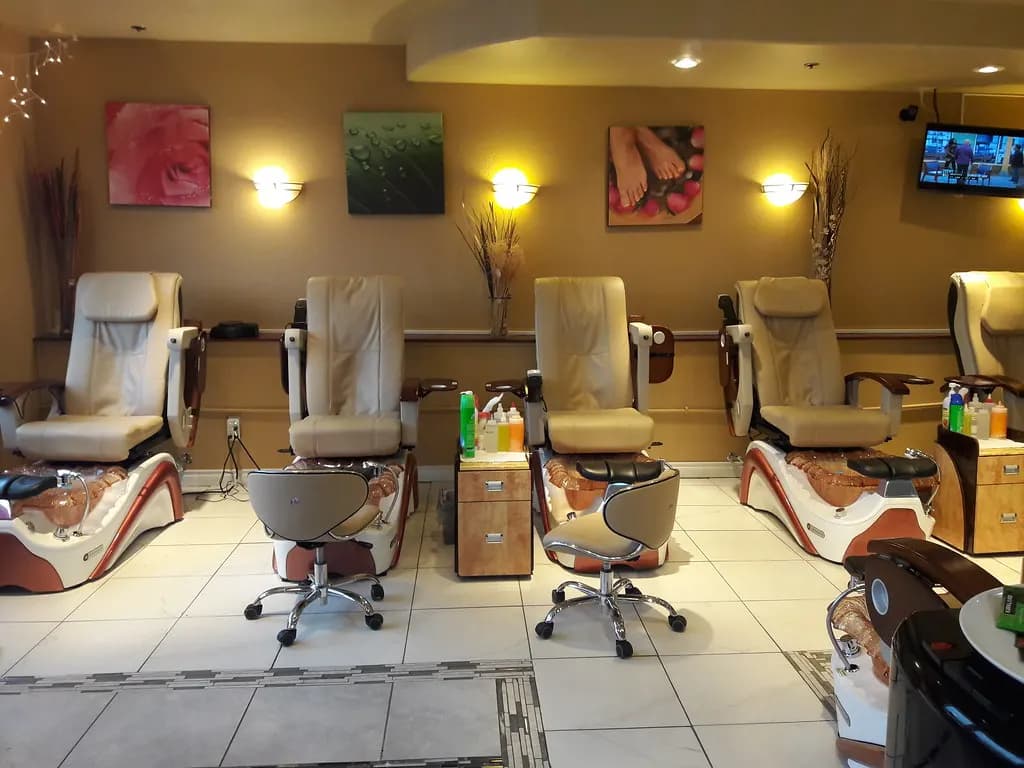 A row of plumbed pedicure spa chairs with technician stools and supply cabinets in a nail salon