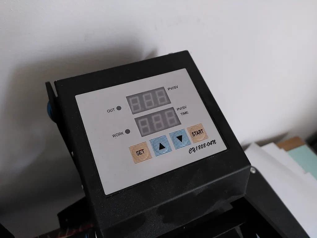 The digital time and temperature control panel of a clamshell heat press used for transfers